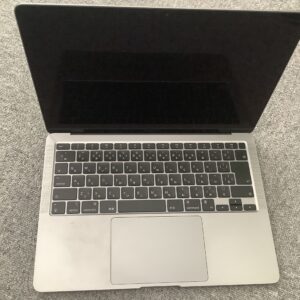 Top-down view of an open silver laptop with a dark screen and black keyboard resting on a textured gray carpet.